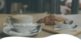 Et topbanner på en hjemmeside der viser en kop kaffe og en croissant